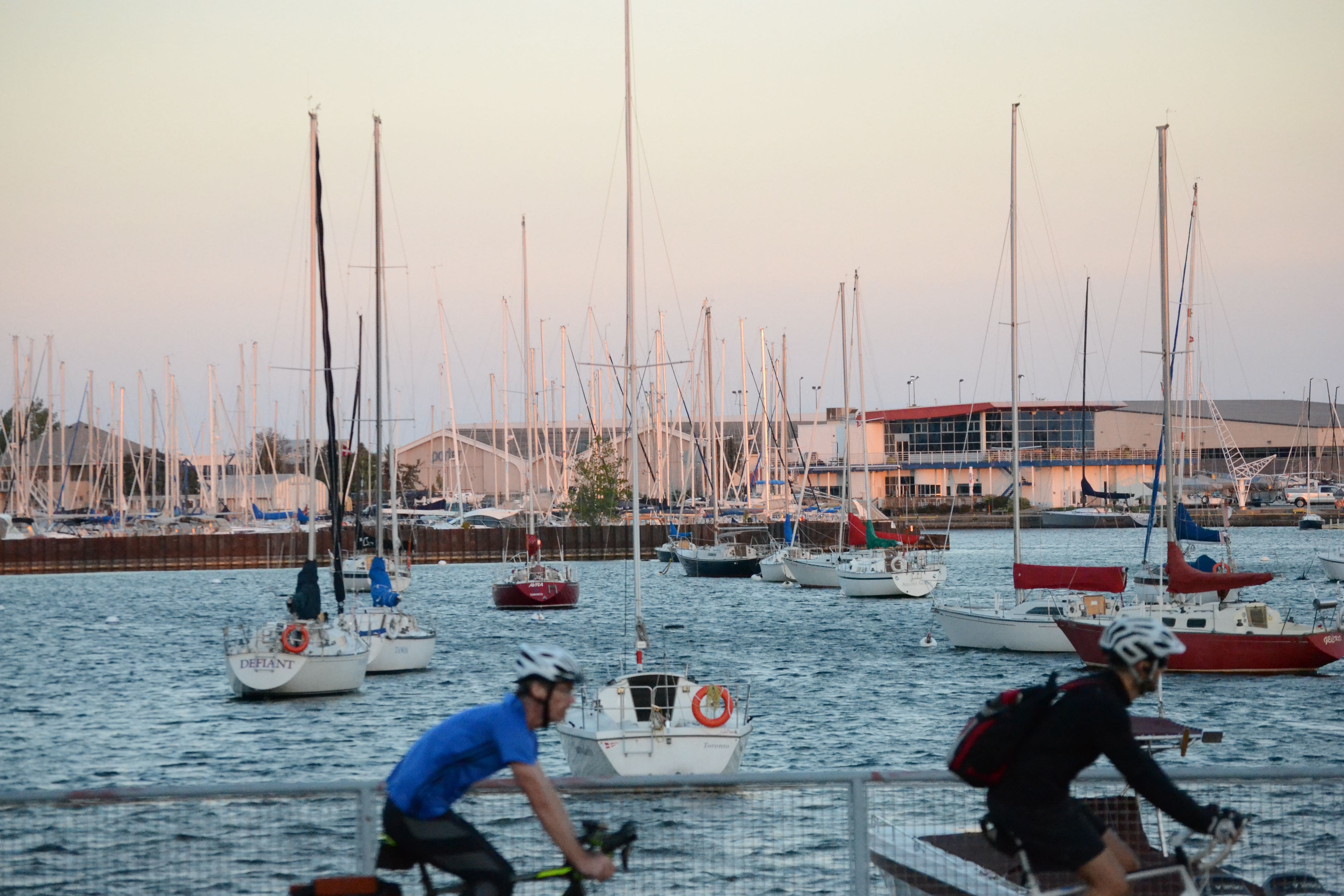 boats in harbour with cyclists passing