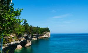 A group of kayakers tours the cliffs of Pictured Rocks National Lakeshore against a striking landscape. Pictured Rocks, Michigan. Recreation. Chris Ingham.