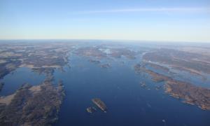 View of the Thousand Islands from an altitude of about 2,000 ft looking SE towards Lake Ontario. View of Ontario and New York. And there's a ship in the river. Alexandria Bay, New York. Great Lakes Water in Action. Michael Twiss.